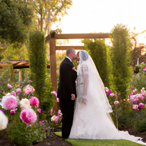 An image of a sun-drenched garden adorned with vibrant flowers, where a radiant bride in an elegant lace gown, and a dapper groom in a tailored suit exchange vows under a cascading arch of blush roses