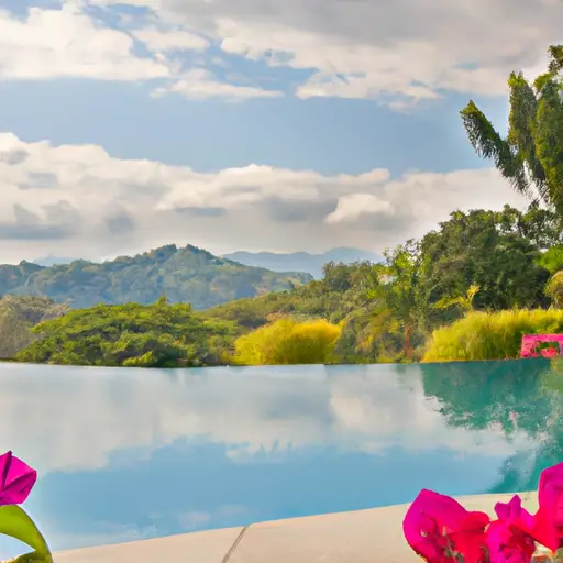 An image capturing a serene outdoor scene at a luxury spa retreat, with a tranquil infinity pool overlooking lush green mountains, surrounded by tall palm trees and vibrant tropical flowers