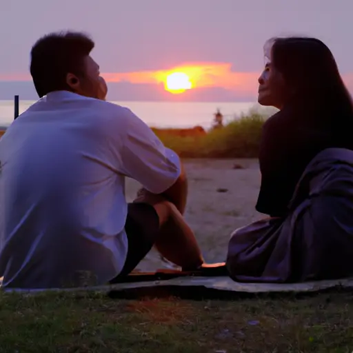  a serene sunset beach scene, where a man and woman sit on a blanket facing each other