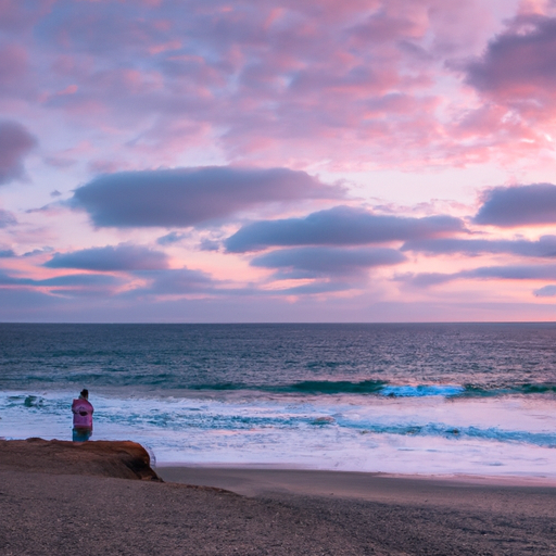 An image depicting a serene beach at sunset, where a person sits alone, gazing at the ocean