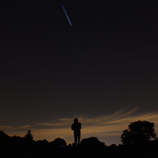 Capture an image of a solitary shooting star streaking across a pitch-black sky, illuminating the silhouette of a person gazing up in wonder, as if the universe is subtly whispering that it's time for a new path